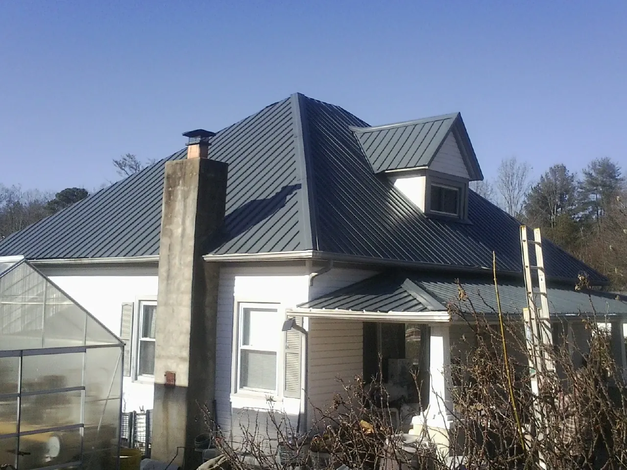 Dark blue standing seam metal roof on a white farmhouse with dormer — Slate & Tile Roof Repair by Roofing Brothers in Allison