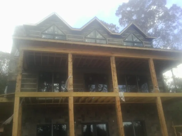 Dormers and porch framing on a large log home under construction — Roof Coating work by our crew in Allison