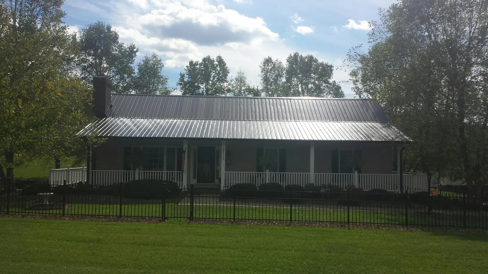 Gray metal roof on a brick ranch with a full width front porch — Gutter Guard Installation work by our crew in Allison