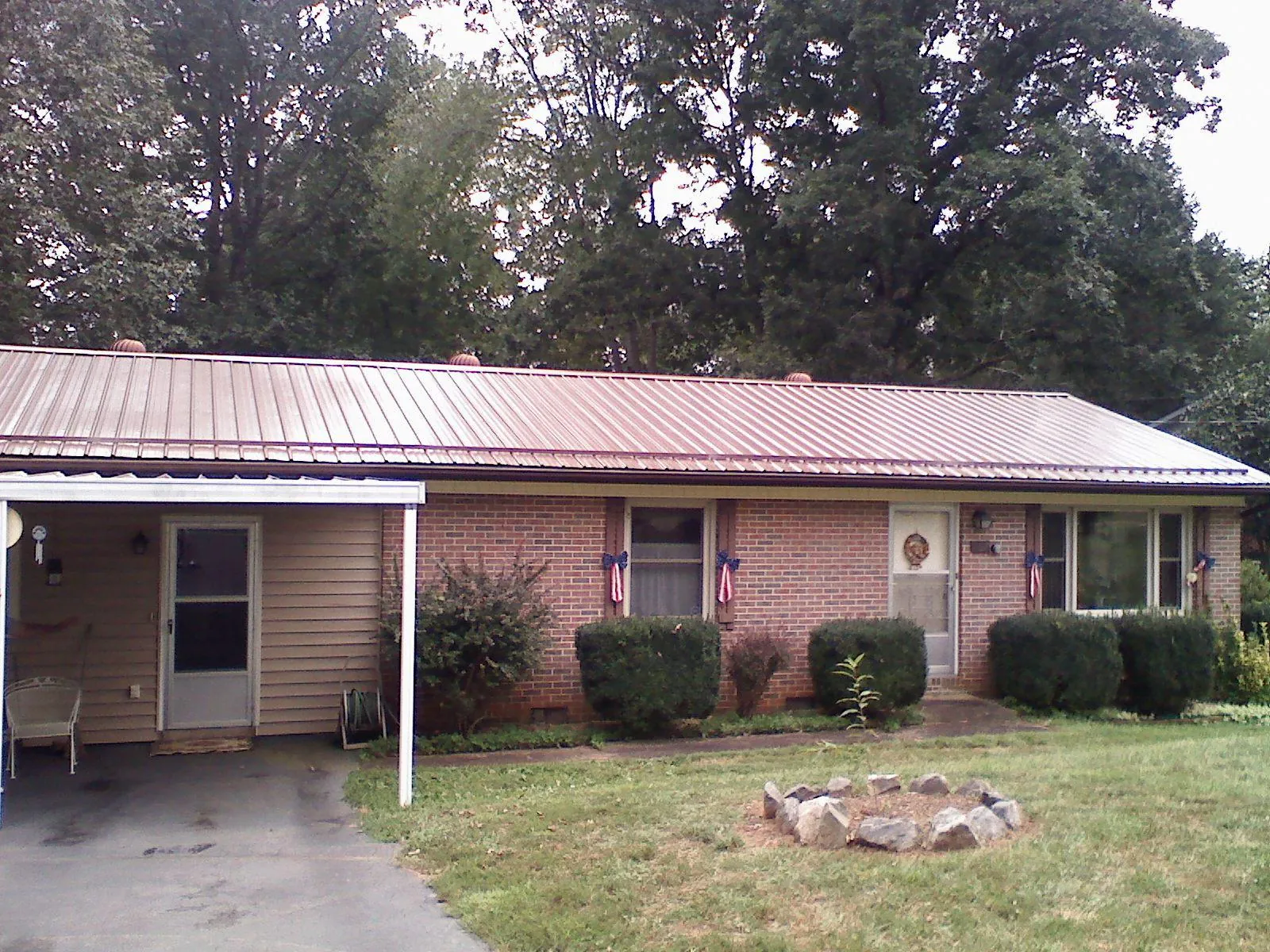 Bronze metal roof and carport on a brick ranch home — Roof Repair work by our crew in Allison