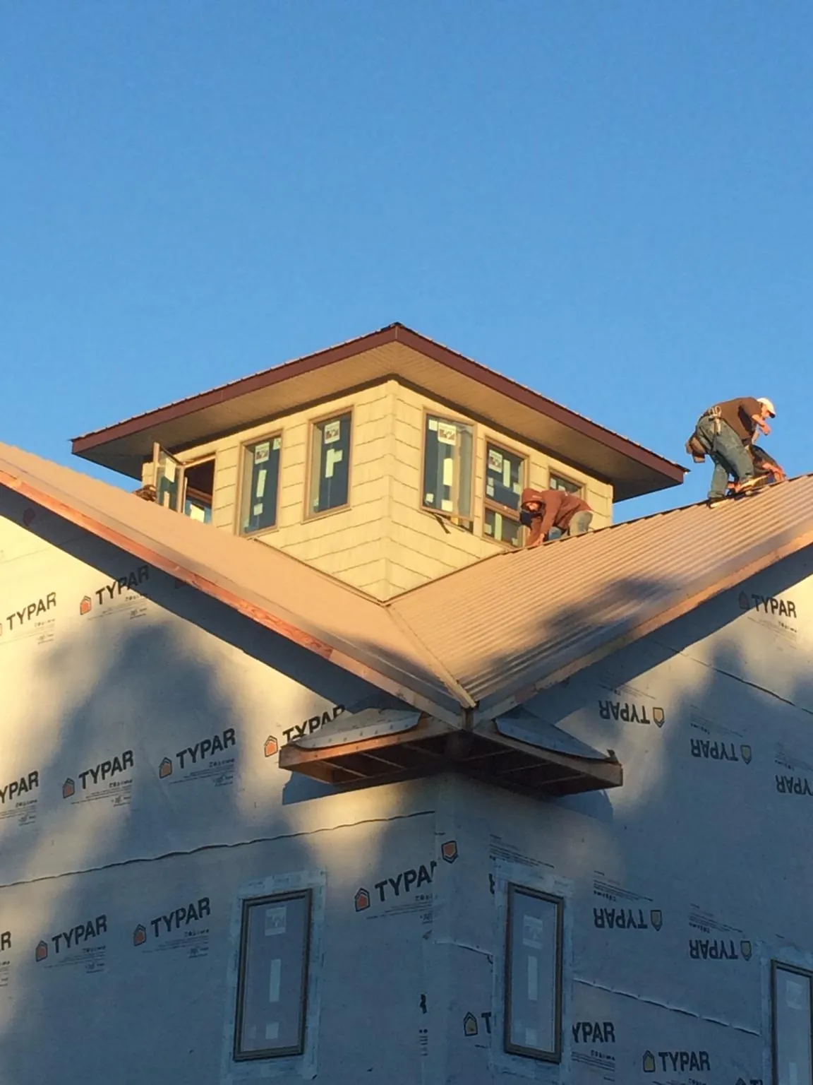 Roofers working around a rooftop cupola on a new metal roof at sunset — Roof Waterproofing in Allison by Roofing Brothers